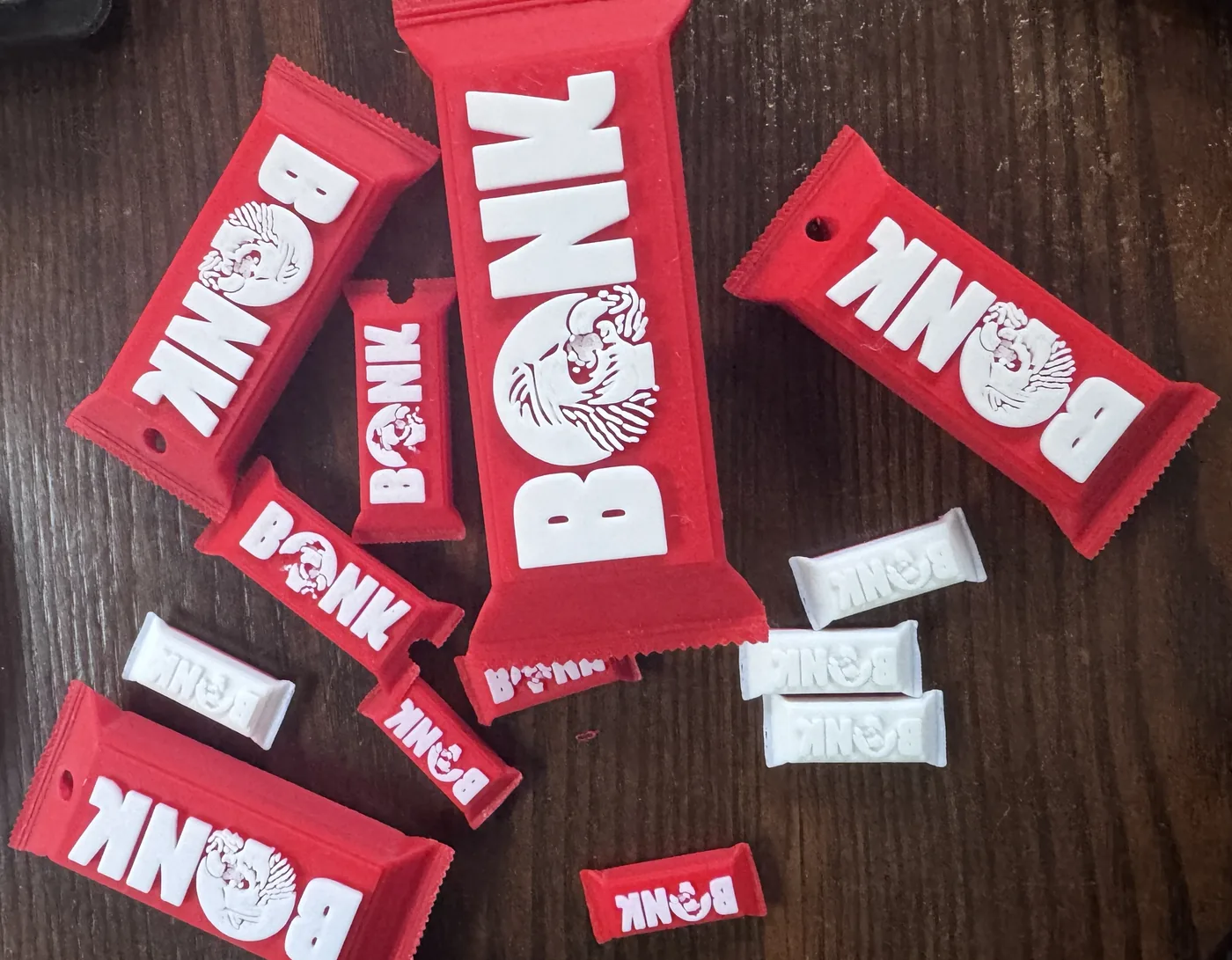 Red and white 3D-printed candy-bar keychains with the BONK logo in several sizes